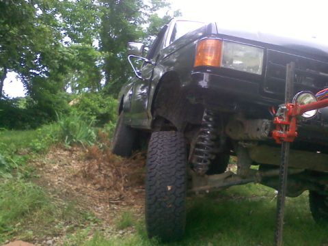 1994 Ford F-150 - This black pickup truck has a lifted suspension and large tires, being jacked up on the front passenger side.