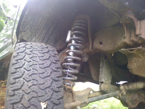 1994 Ford F-150 - This image shows the suspension system of a vehicle, including the tire and shock absorber, with visible rust on the frame.