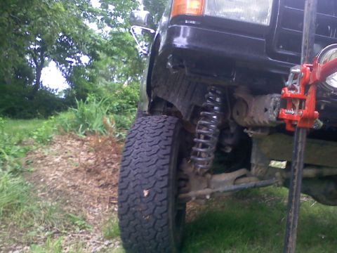 1994 Ford F-150 - Front suspension and fender of a black 1992 Ford F-150 truck with a jack attached.