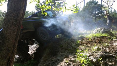 1994 Ford F-150 - A truck navigates a challenging off-road course, kicking up dust and smoke.