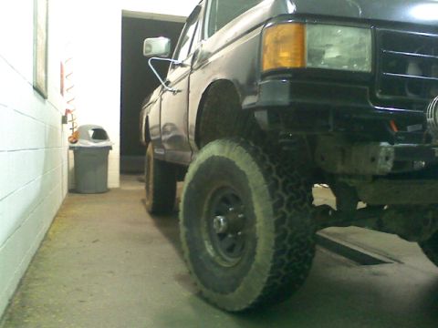 1994 Ford F-150 - This lifted Ford F-150 truck has large off-road tires and appears to be in a garage or service bay.