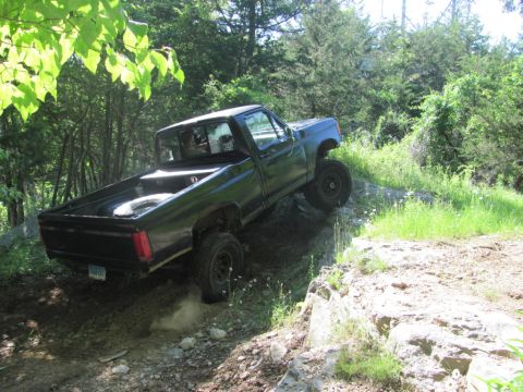 1994 Ford F-150 - Pickup truck navigating a challenging off-road course with large rocks and steep inclines.