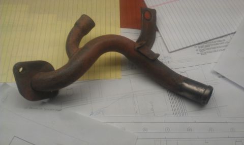 1991 Ford Festiva - A rusty metal pipe with a mounting flange sits on top of technical drawings and graph paper.