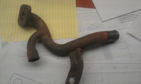1991 Ford Festiva - A rusty metal pipe with a flange sits on top of technical blueprints.