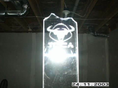 1998 Mercury Sable - A glass plaque with a bull logo and text is illuminated, set against a backdrop of exposed ceiling infrastructure.