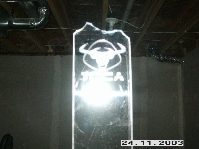 Glass plaque with bull logo and 'TCEA' text. Background shows ceiling and wall