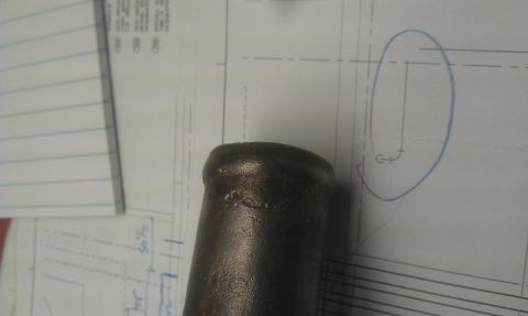 1991 Ford Festiva - A close-up view of a metal pipe positioned over technical drawings and blueprints, with some handwritten annotations visible.