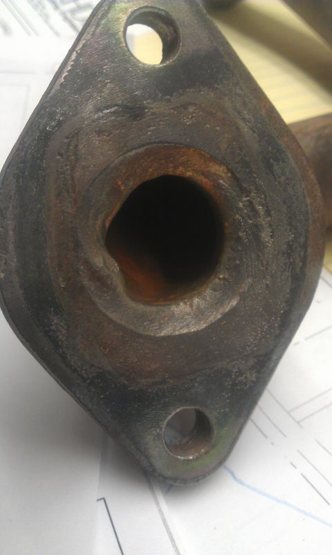 1991 Ford Festiva - This is a close-up of a rusty exhaust manifold flange, showing its two bolt holes and the opening for exhaust gases.