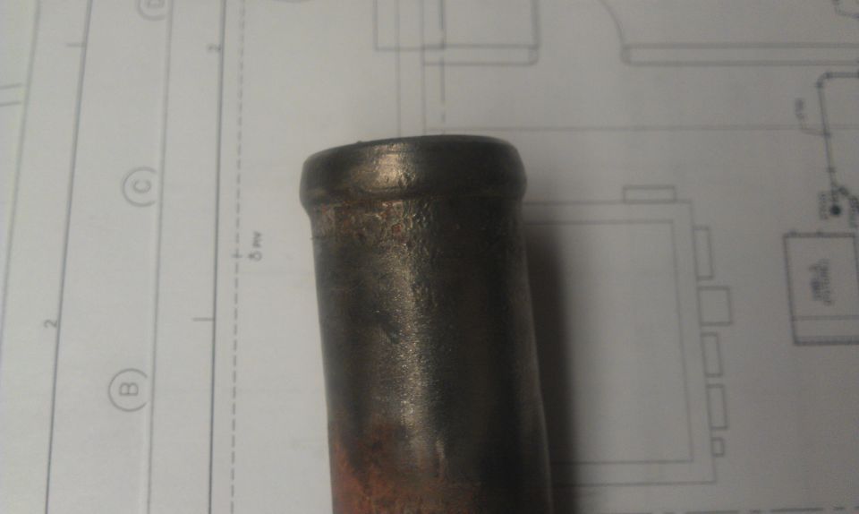 Close-up of a metal pipe resting on blueprints with diagrams