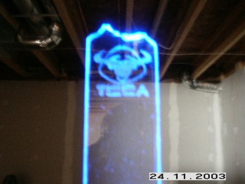 1998 Mercury Sable - A blue neon sign with a bull logo and the word 'TECA' is illuminated against a background of ceiling joists and walls.