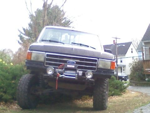 1994 Ford F-150 - A lifted Ford F-series truck with a winch is parked in a residential area.