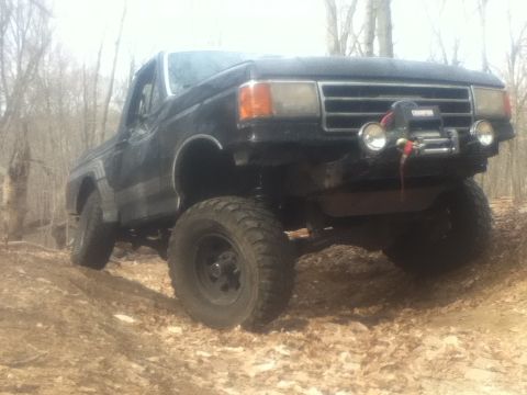 1994 Ford F-150 - This lifted truck is equipped with a winch and is navigating an off-road trail.