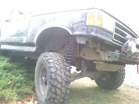 1994 Ford F-150 - A black Ford F-Series truck with a lifted suspension and off-road tires is shown from a low angle.