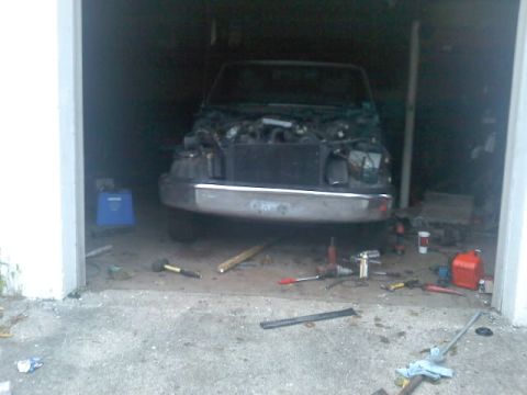 1994 Ford F-150 - The front of a truck is visible in a garage, with the hood open and tools on the ground.