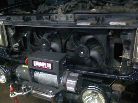 1994 Ford F-150 - The front of a vehicle is shown with the grille removed, revealing dual electric fans and a winch. Fog lights are visible on the lower bump…