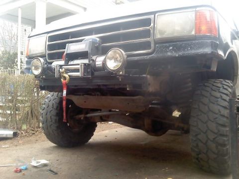 1994 Ford F-150 - The front of a truck is shown with a winch mounted on the bumper and large off-road tires.