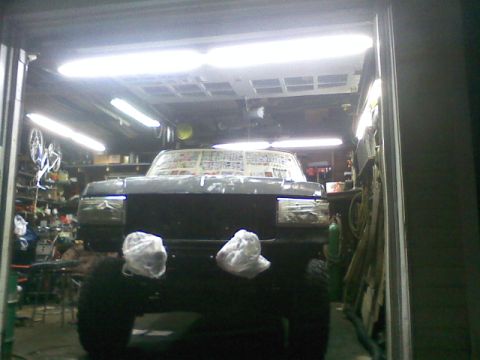 1994 Ford F-150 - A truck is parked inside a garage, its windshield covered with paper, possibly for painting or protection.