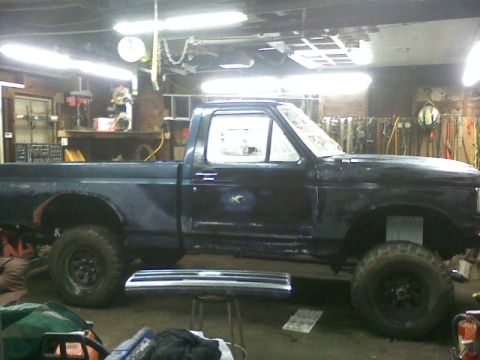 1994 Ford F-150 - A dark blue pickup truck is parked inside a garage, with tools and equipment visible in the background.