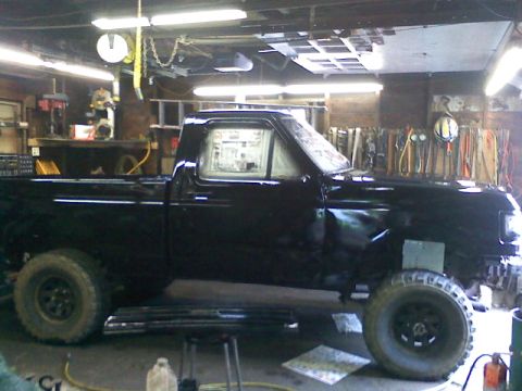 1994 Ford F-150 - A black 1994 Ford F-150 pickup truck is seen from the side, parked inside a garage with tools on the wall.