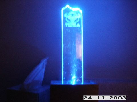 1998 Mercury Sable - A blue illuminated acrylic sculpture with text and a logo is displayed on a dark surface.