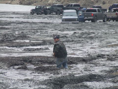 1978 Ford Bronco - Multiple vehicles are stuck in a muddy area, with a man standing in the mud.