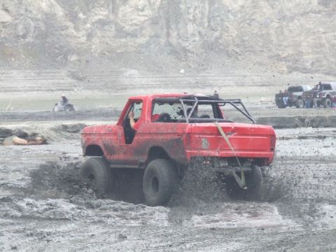 1978 Ford Bronco - A red 1978 Ford Bronco navigates a muddy track with a roll cage.