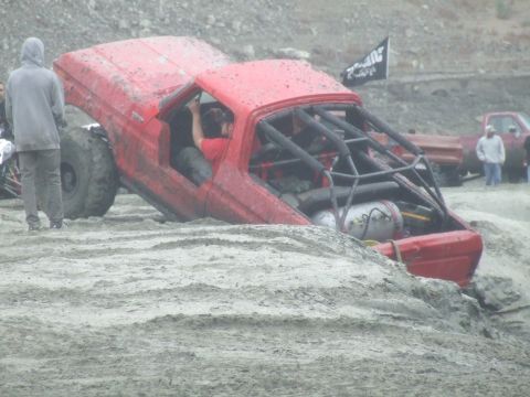 1978 Ford Bronco - Off-road vehicle with extensive roll cage modification is stuck in a muddy terrain.