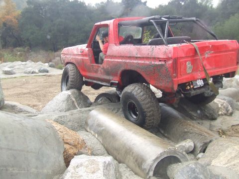 1978 Ford Bronco - This modified SUV is navigating a challenging rocky terrain, with a driver at the wheel.