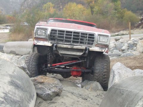 1978 Ford Bronco - This modified truck is shown off-roading over large rocks and uneven terrain.