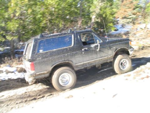 1988 Ford Bronco - This black Ford Bronco is captured mid-action on a snowy, muddy trail.