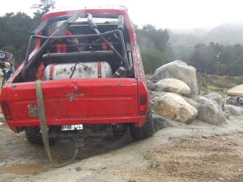 1978 Ford Bronco - A modified red pickup truck navigates a rocky obstacle course on a foggy day.