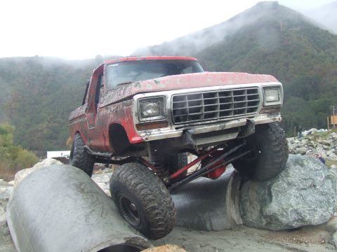 1978 Ford Bronco - This modified 1978 Ford Bronco is shown tackling a challenging off-road course with large rocks and concrete pipes.