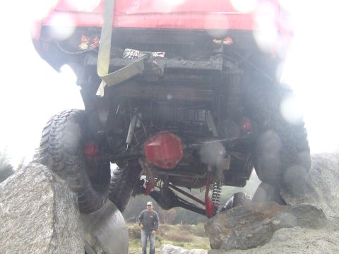 1978 Ford Bronco - A red SUV is stuck on rocks, with its undercarriage and large tires visible.
