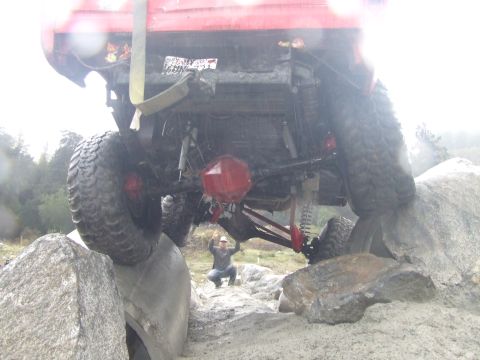 1978 Ford Bronco - A red off-road vehicle navigates a rocky obstacle course, with a person observing from below.