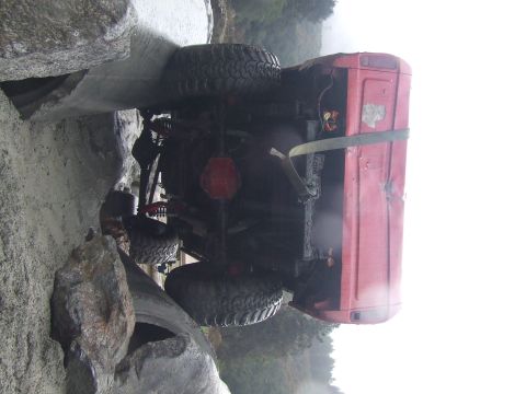 1978 Ford Bronco - Off-road vehicle stuck on rocks, showing its undercarriage and rear tire.