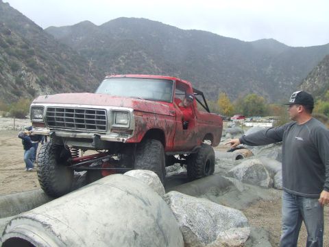 1978 Ford Bronco - A red 1978 Ford Bronco navigates a rocky obstacle course with a man pointing.