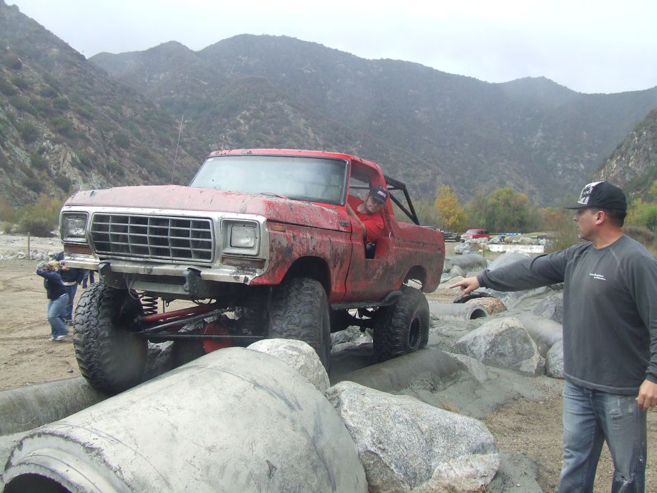 Red 1978 Ford Bronco on rocks, front 3/4 view