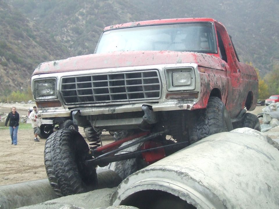 1978 Ford Bronco with lifted suspension driving over concrete pipes