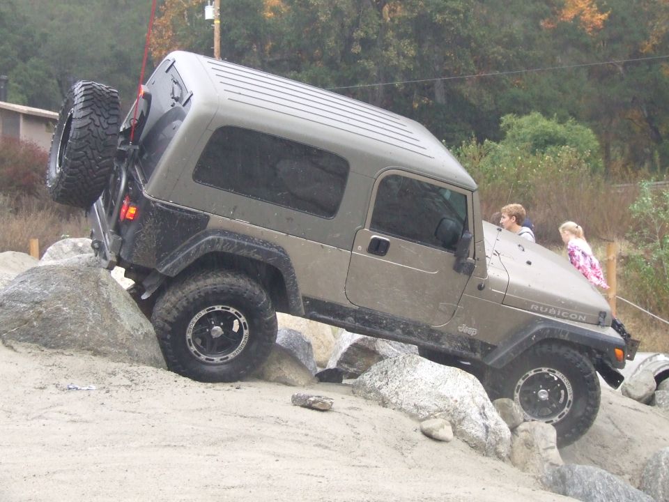 Jeep Wrangler Rubicon on rocks, two kids on hood