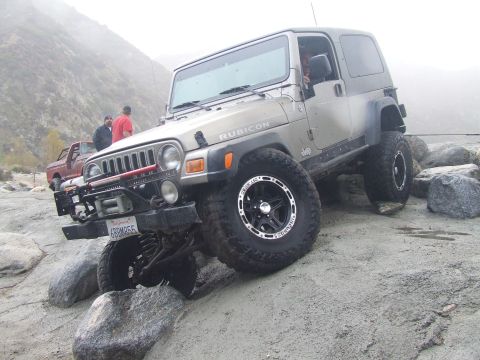 1978 Ford Bronco - A silver Jeep Wrangler Rubicon navigates a rocky terrain, with another vehicle visible in the background.