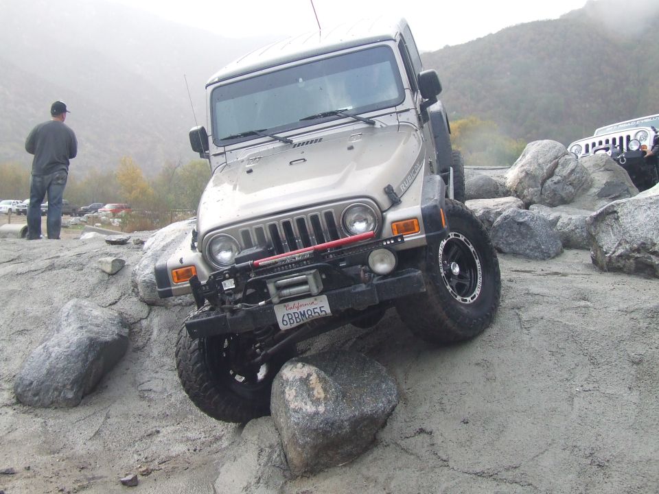 Jeep Wrangler TJ navigating rocky terrain, another Jeep visible in background