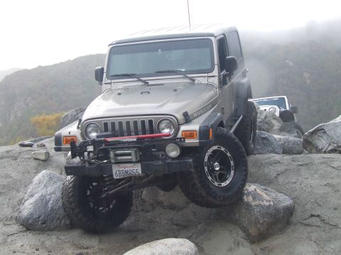 1978 Ford Bronco - A silver Jeep Wrangler Rubicon navigates a rocky trail, with another Jeep visible in the background.