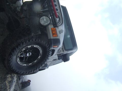 1978 Ford Bronco - Vehicle is positioned precariously on rocks with a person visible below.