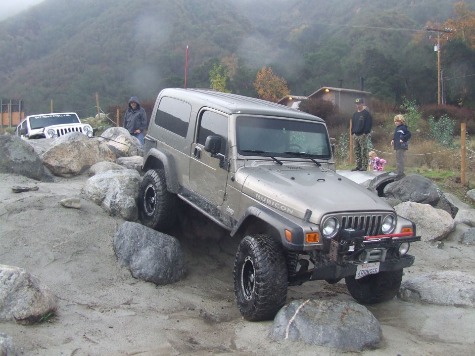 Silver Jeep Wrangler Rubicon navigating rocks, another white Jeep in background