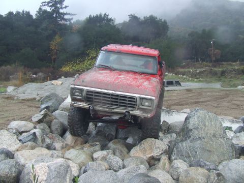 1978 Ford Bronco - This red 1978 Ford Bronco is shown off-roading over a pile of large rocks.