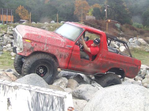 1978 Ford Bronco - A red 1978 Ford Bronco navigates a rocky obstacle course with its driver visible.