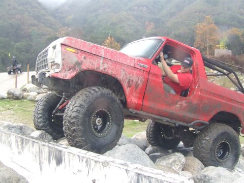 1978 Ford Bronco - A red 1978 Ford Bronco navigates a rocky obstacle course, with another vehicle visible in the background.
