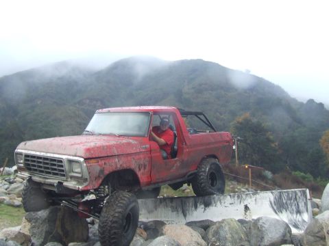 1978 Ford Bronco - A red SUV navigates a challenging obstacle course with a driver inside.