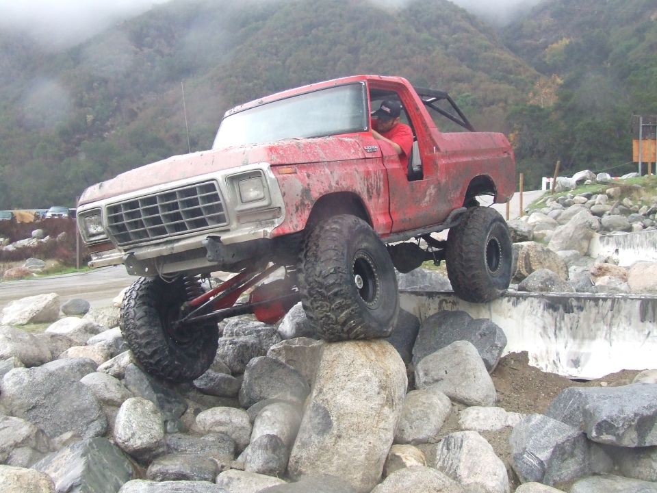 1978 Ford Bronco climbing over large rocks on an off-road course