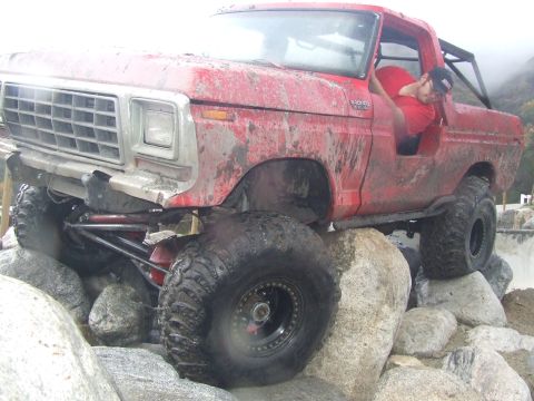 1978 Ford Bronco - A red off-road SUV navigates a rocky obstacle course with a person inside.